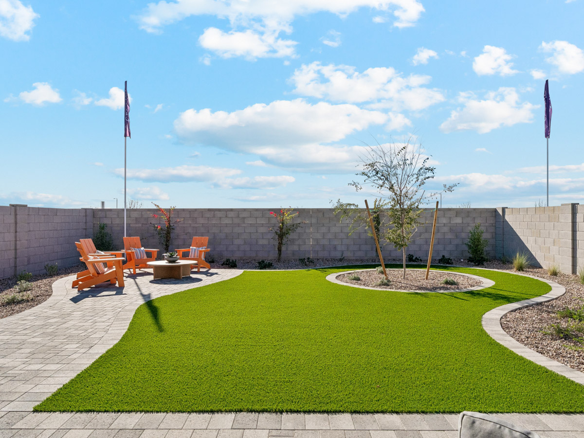 A backyard with a brick wall and a flagpole and a tree.