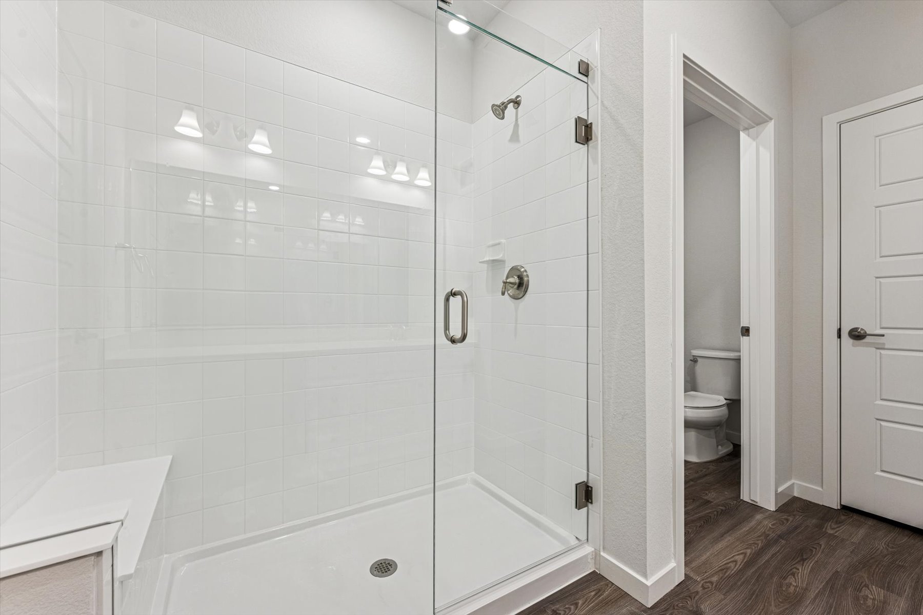 A bathroom with a shower unit and toilet.