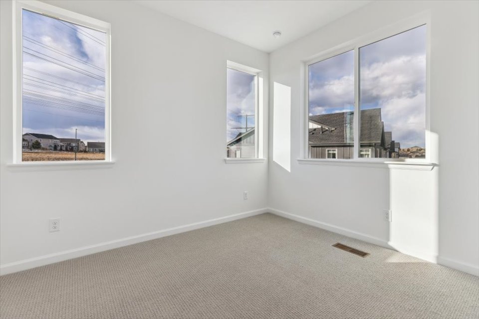 A room with a window and a white wall with a picture of a city.
