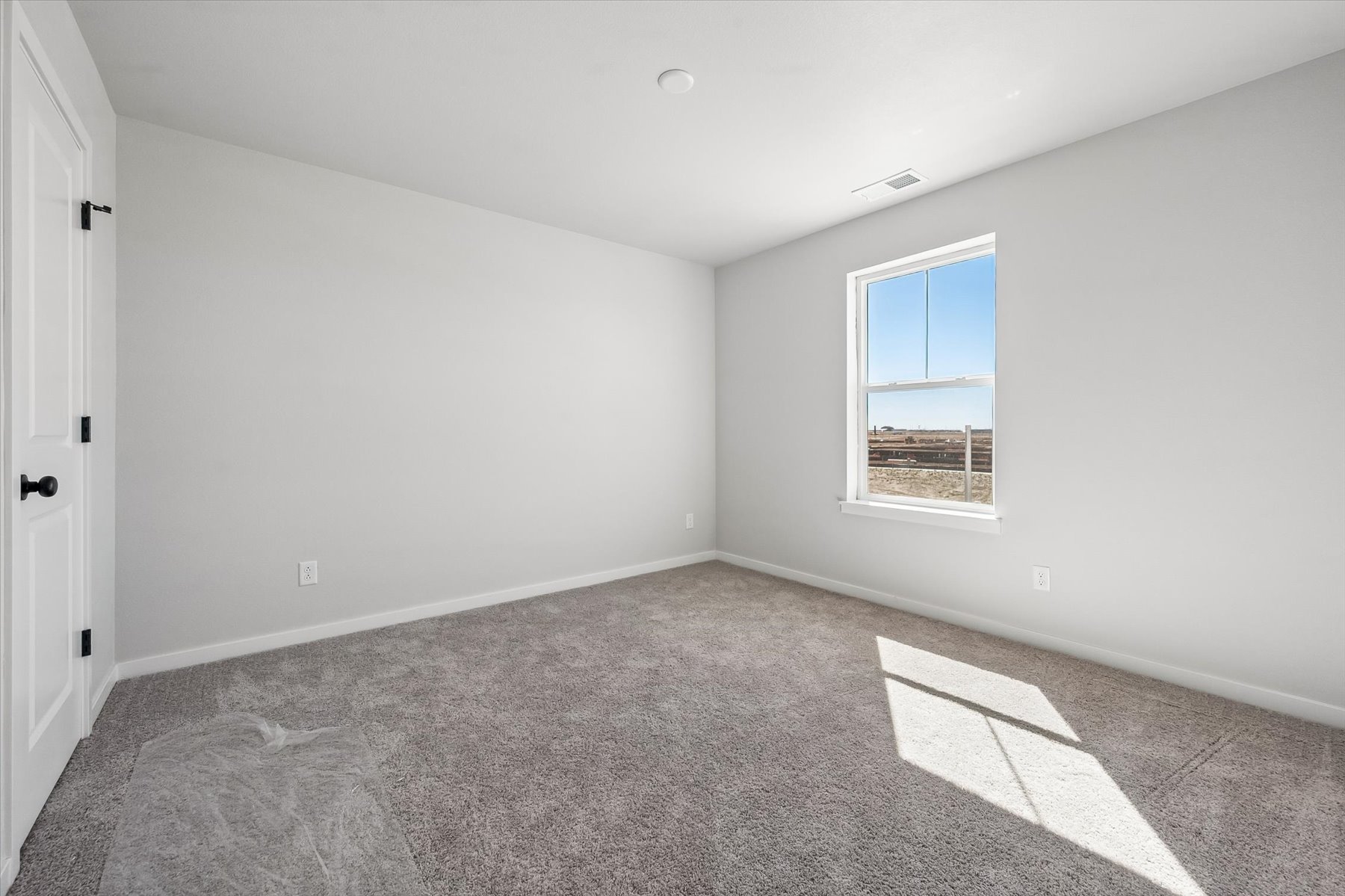 A room with a carpet and a window.