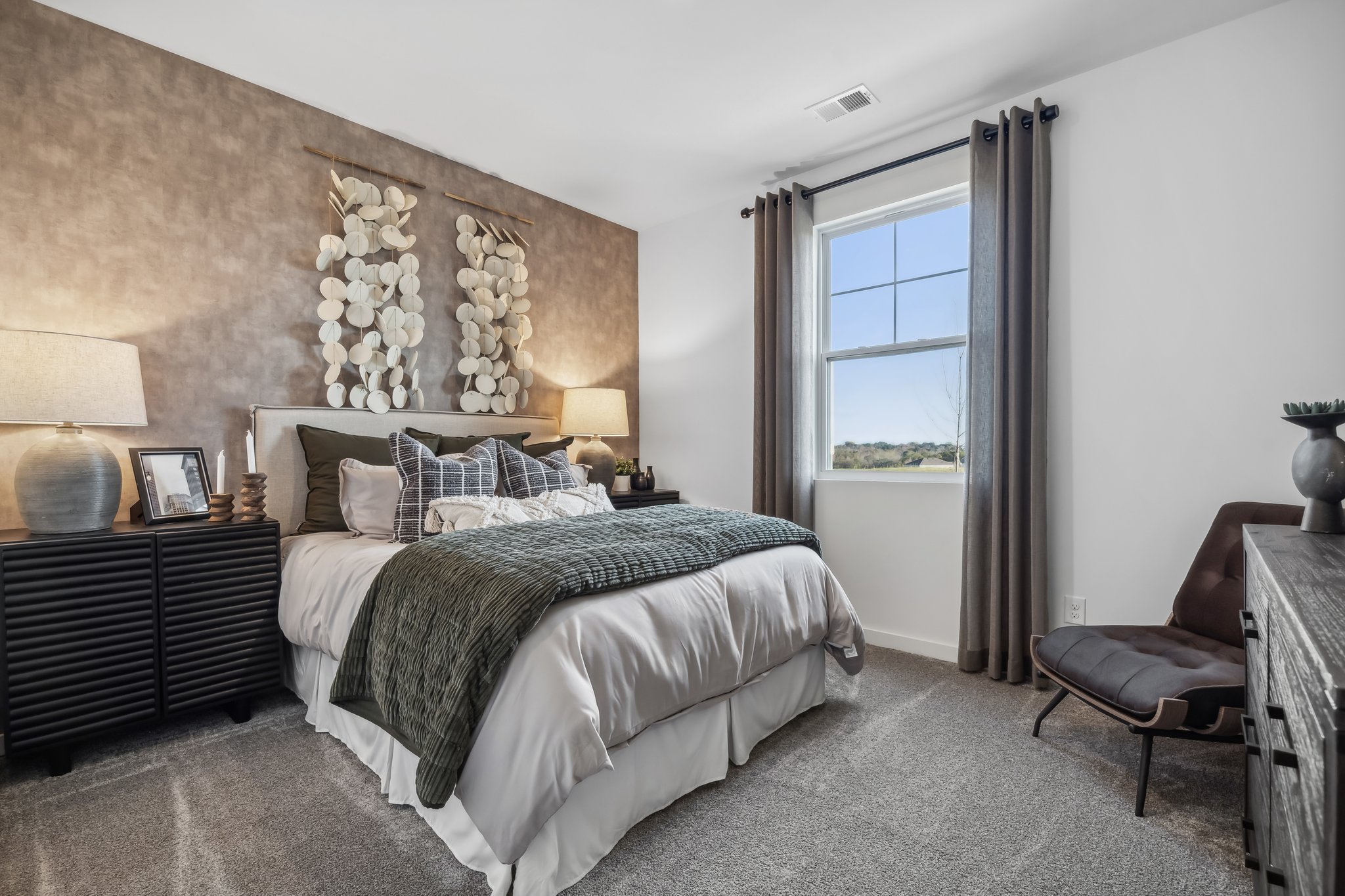 A bedroom with a bed and a chair.