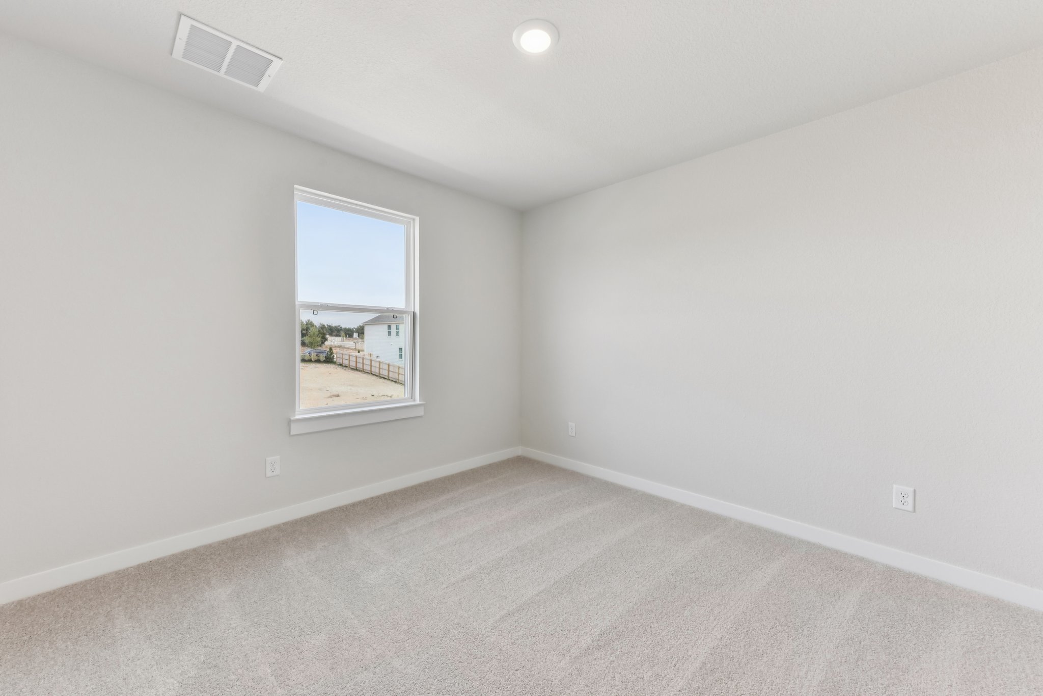 A room with a window and a white wall.
