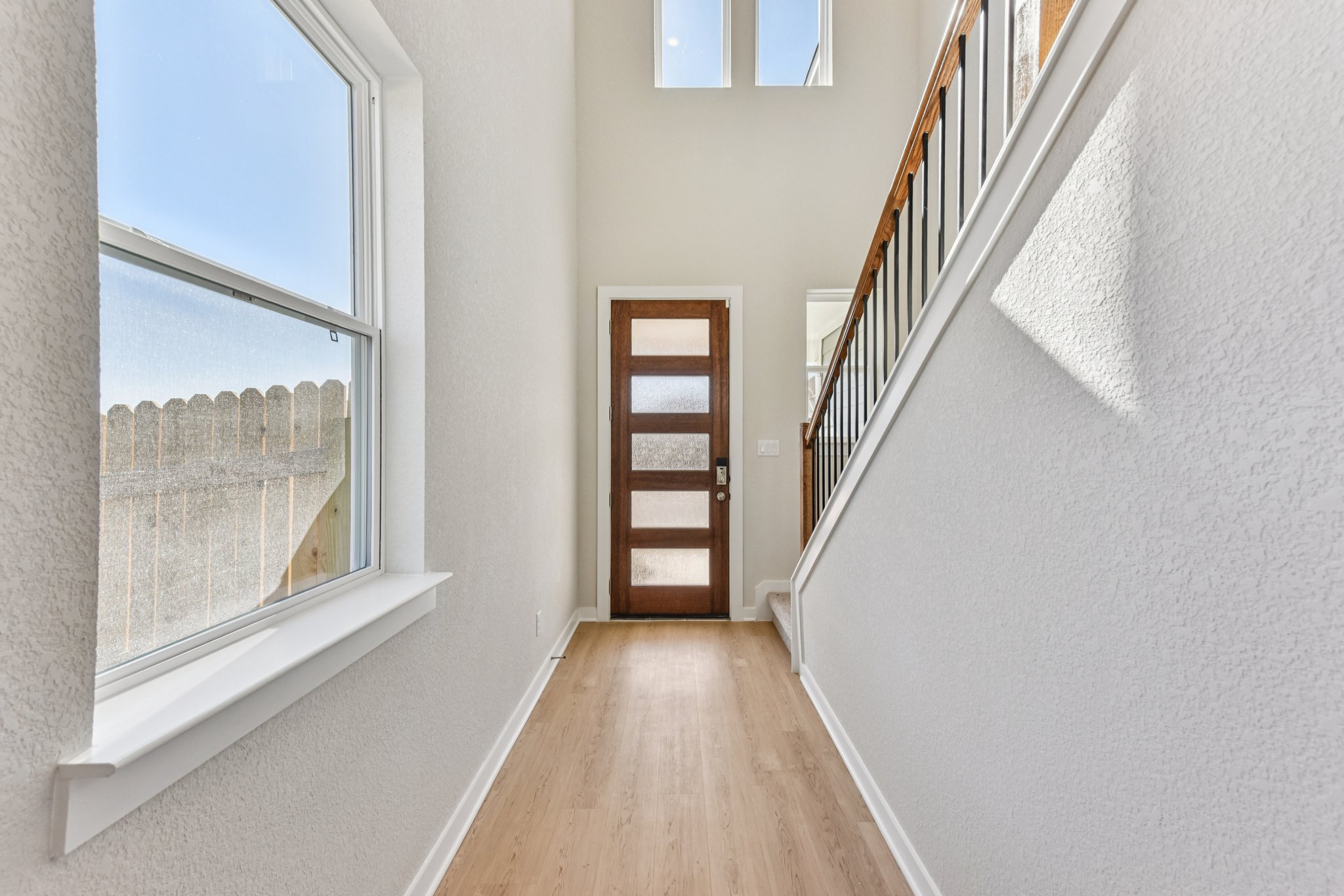 A hallway with windows and a wood floor.