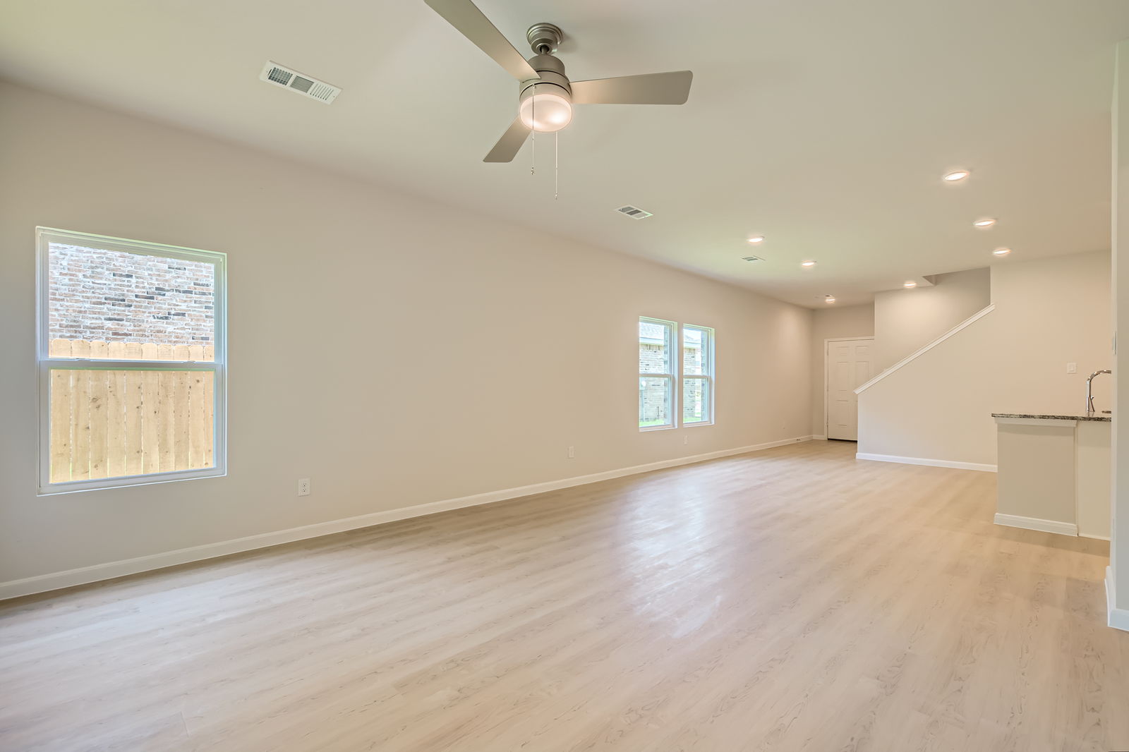 A large empty room with a wood floor and a ceiling fan.