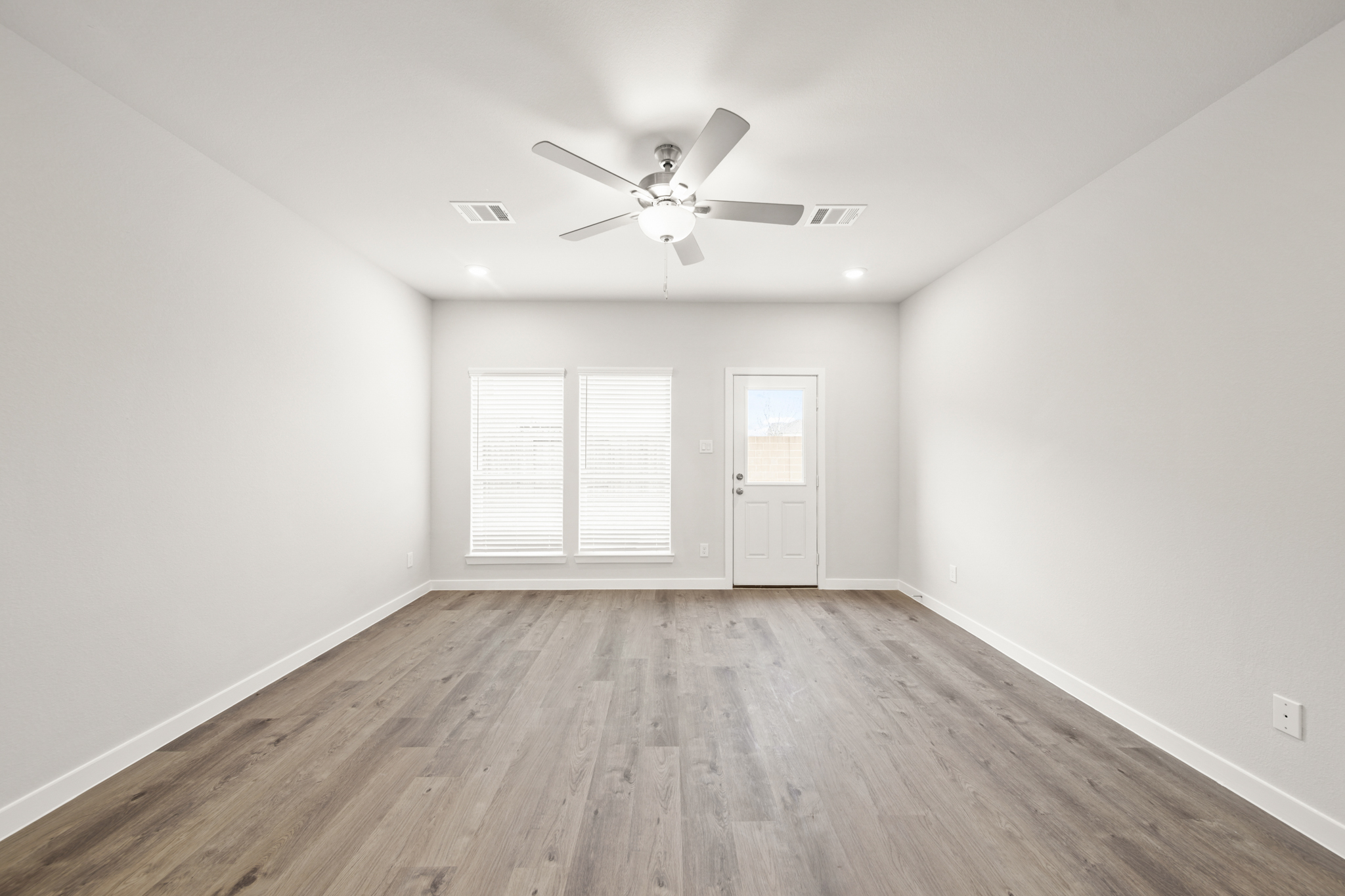 A room with a ceiling fan and a wood floor.