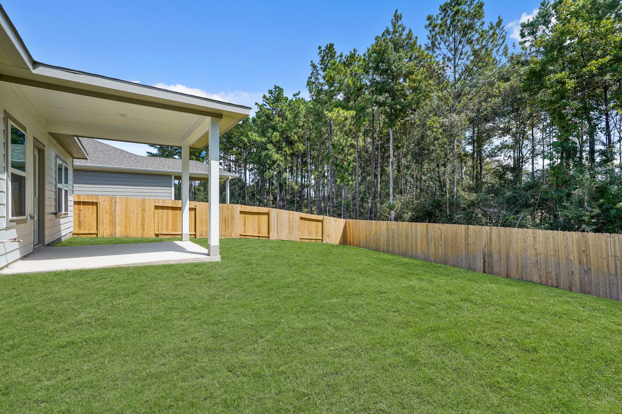 A fenced in yard with a house and trees in the background.