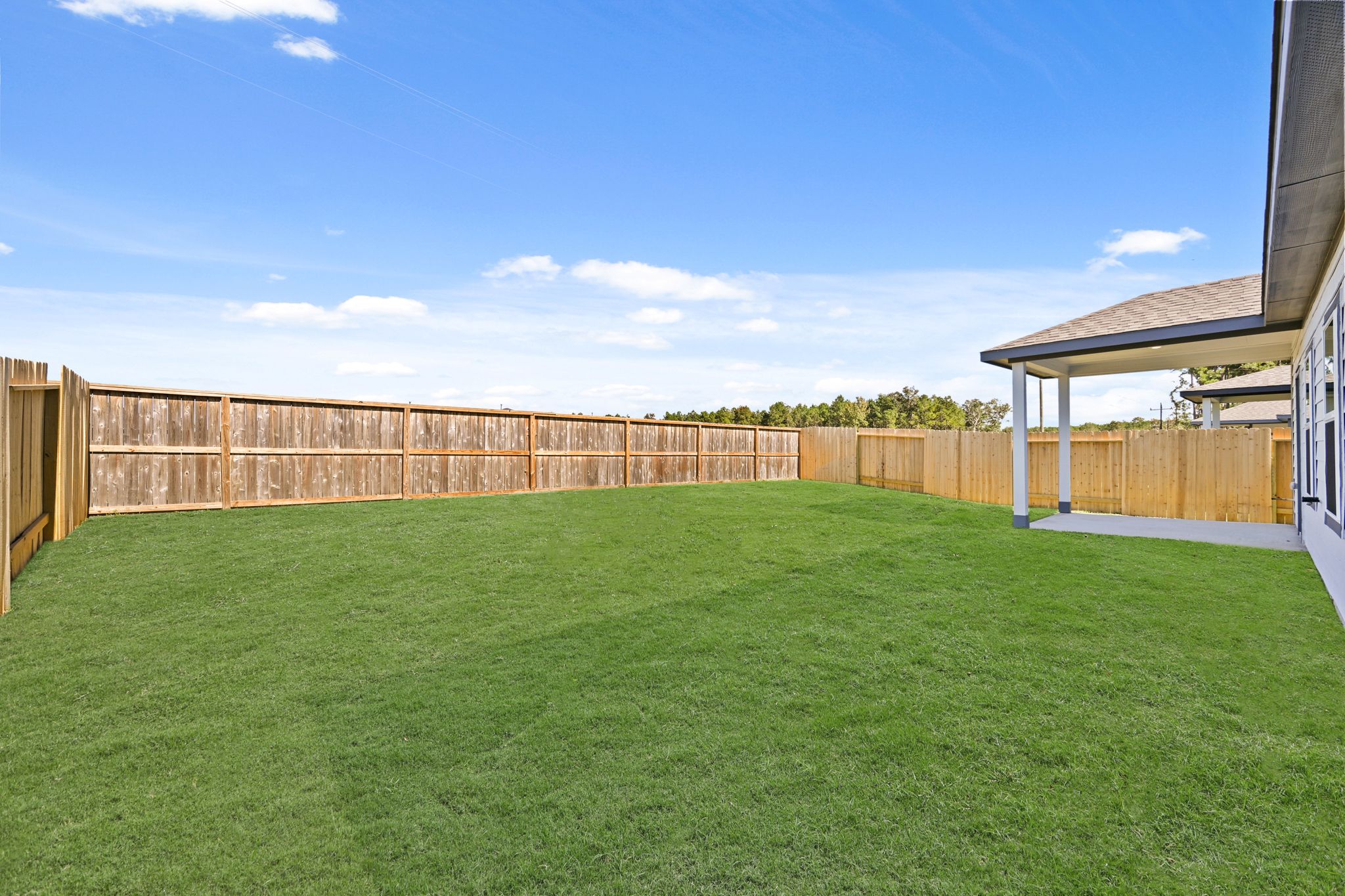 A green lawn in front of a fence and a building.