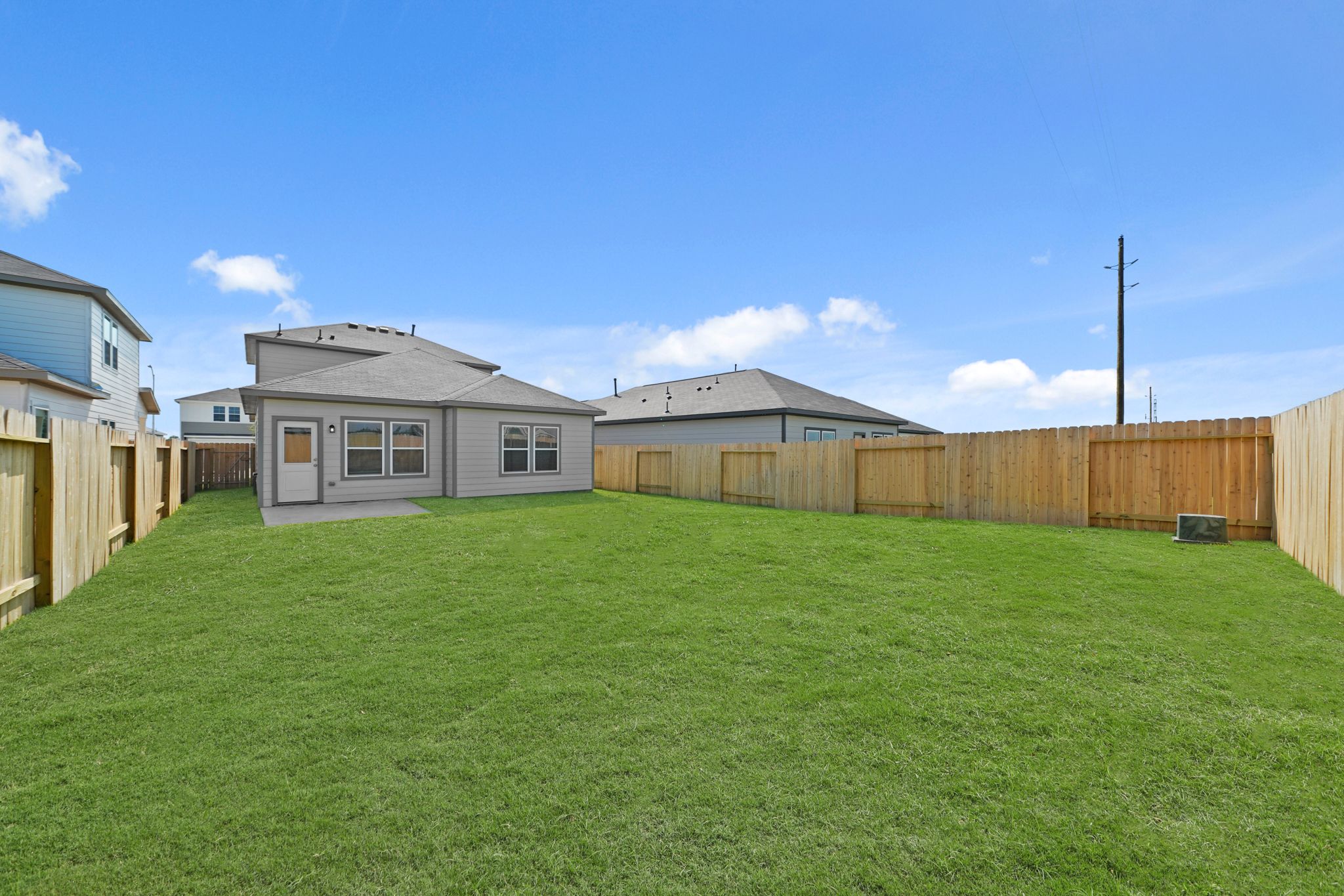 A grassy yard with a fence and buildings in the background.