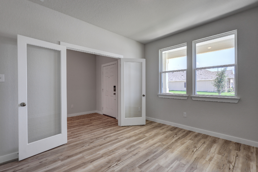 A room with a wood floor and a window with a view of a city.