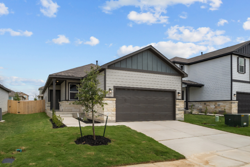 A house with a garage and a tree in the front.