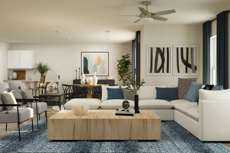 A living room with a large white couch and a table with a plant.