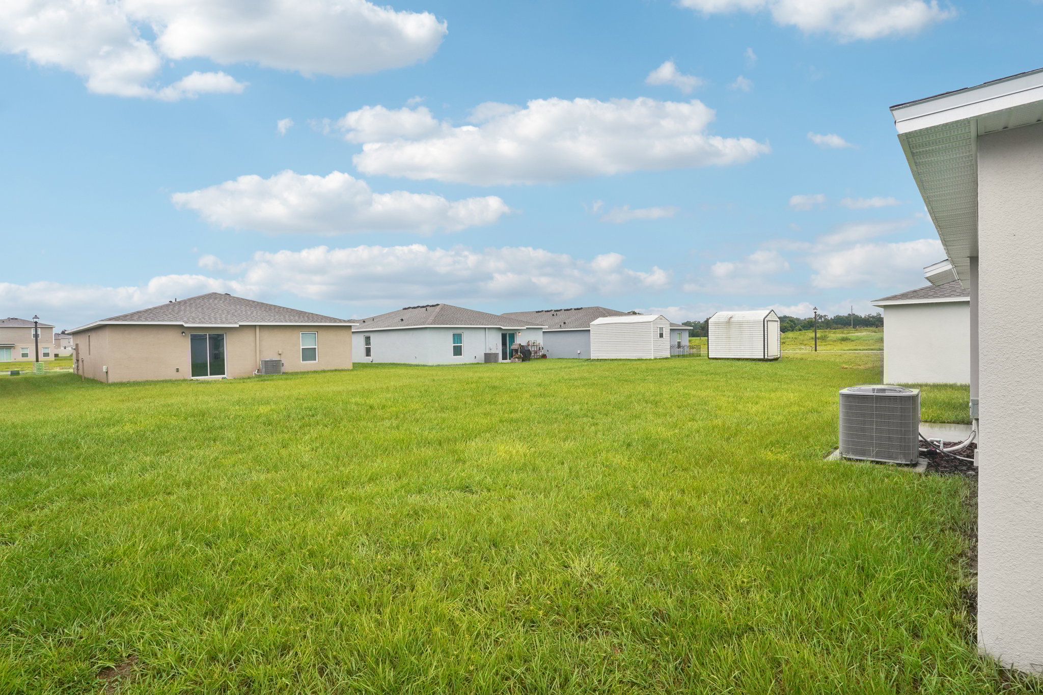 A grassy field with buildings in the background.
